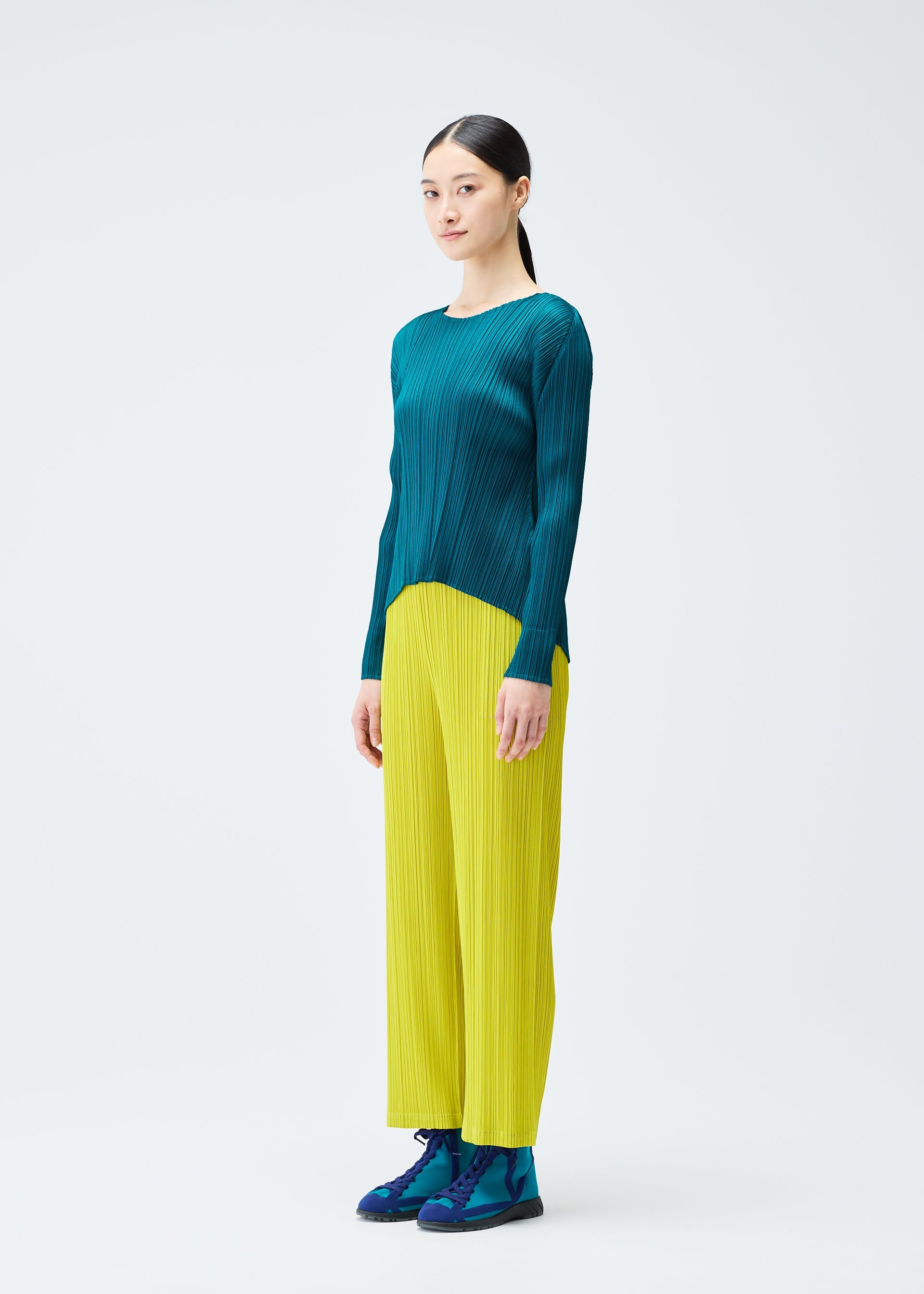 A model wears the PLEATS PLEASE ISSEY MIYAKE MONTHLY COLORS OCTOBER trousers.