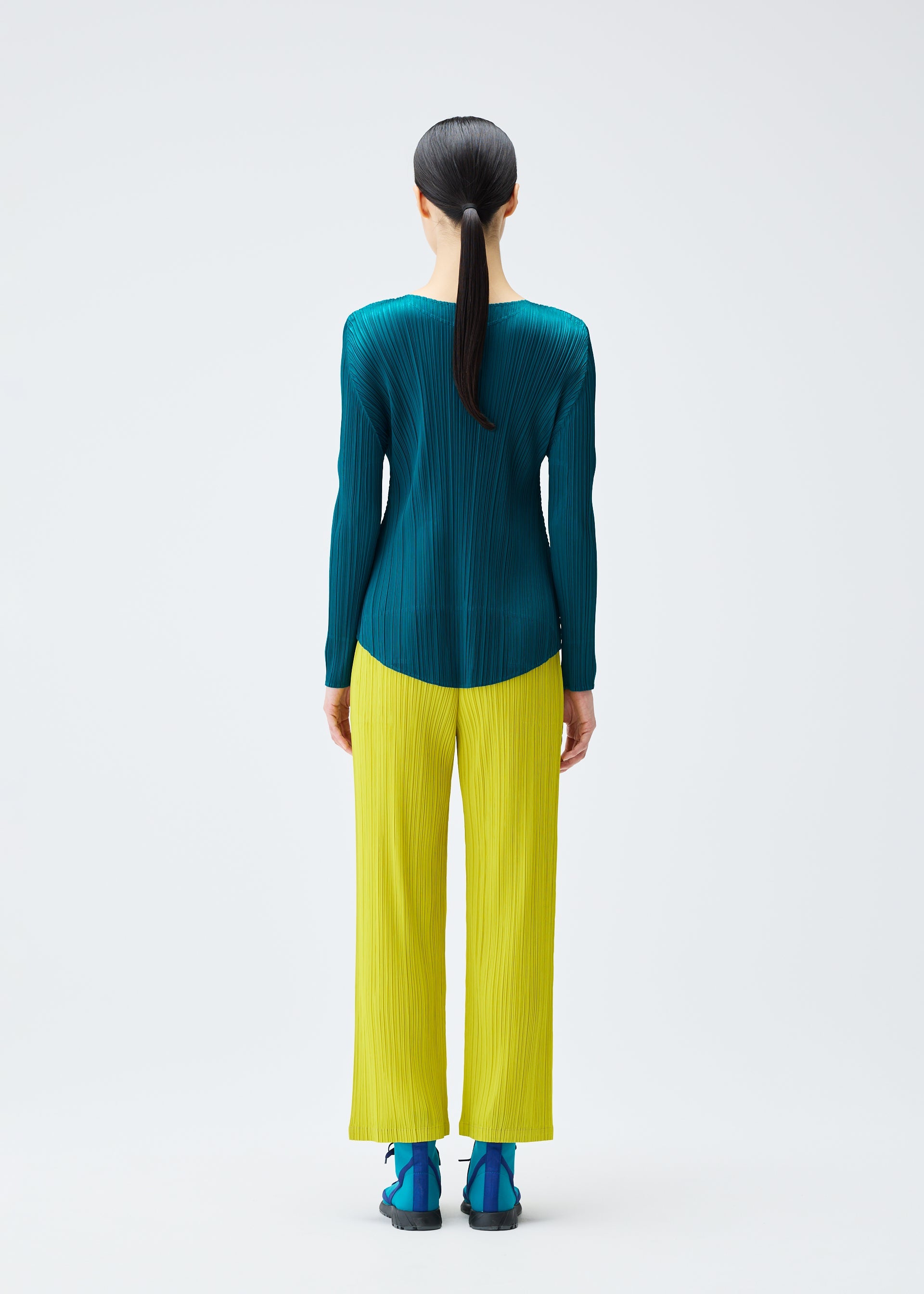 A model wears the PLEATS PLEASE ISSEY MIYAKE MONTHLY COLORS OCTOBER trousers.