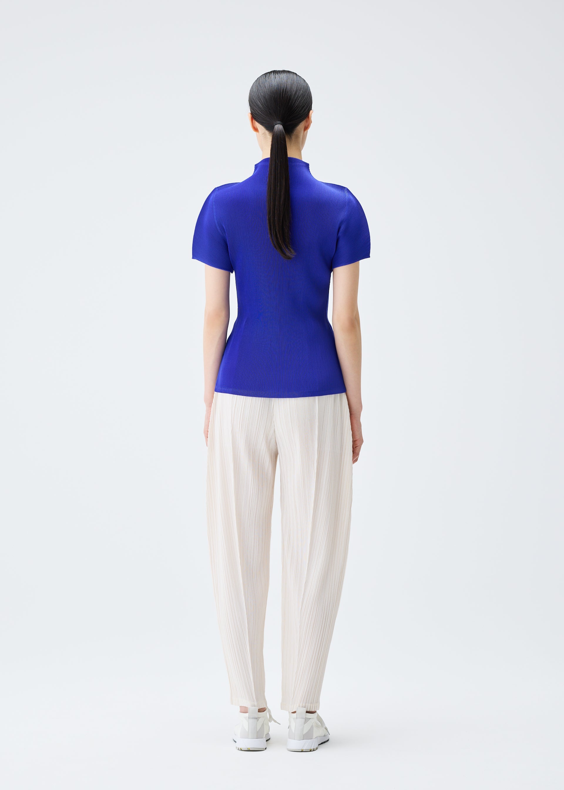 A model wears the PLEATS PLEASE ISSEY MIYAKE THICKER BOTTOMS 2 trousers.