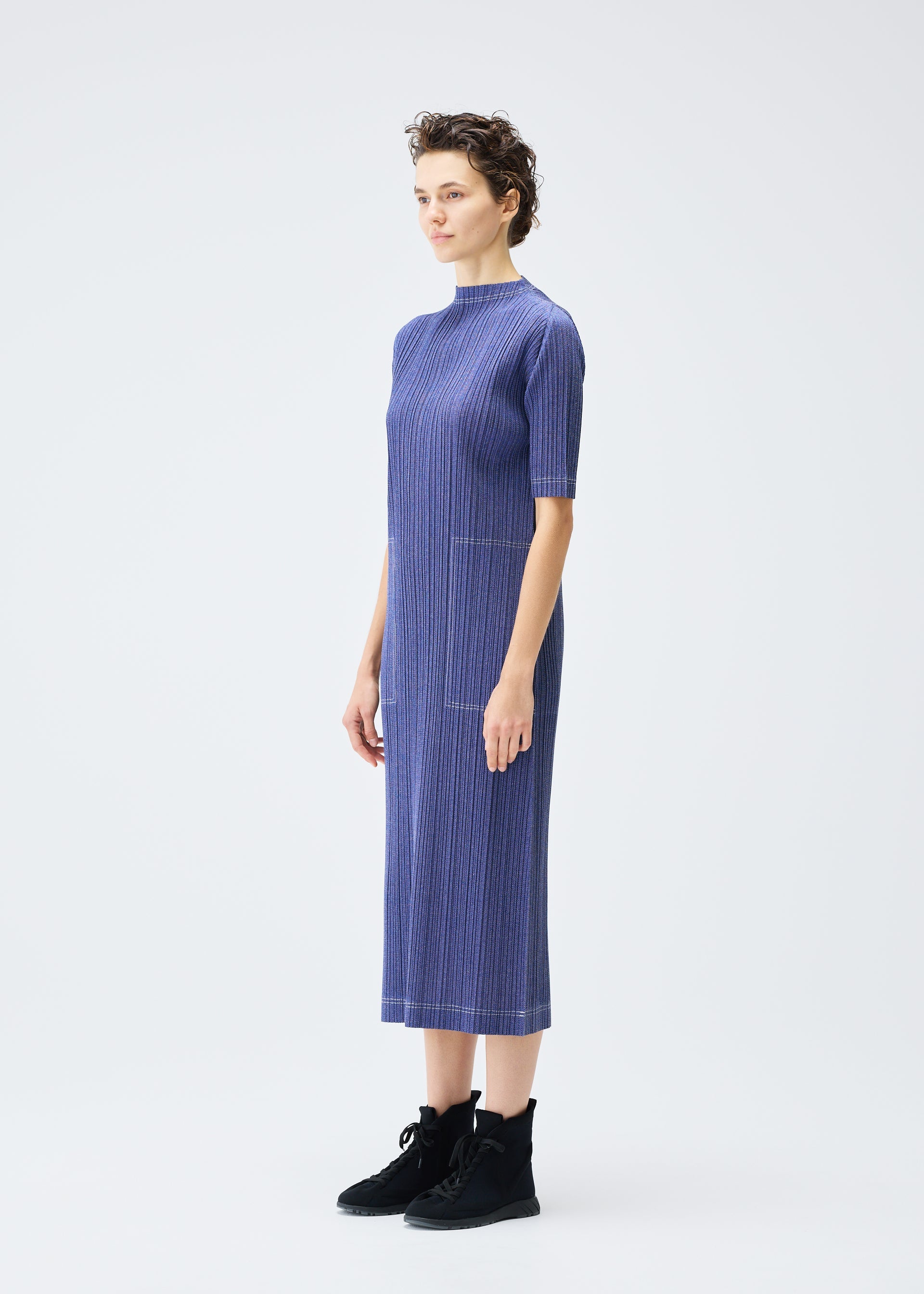 A model wears the PLEATS PLEASE ISSEY MIYAKE COTTON DENIM dress.