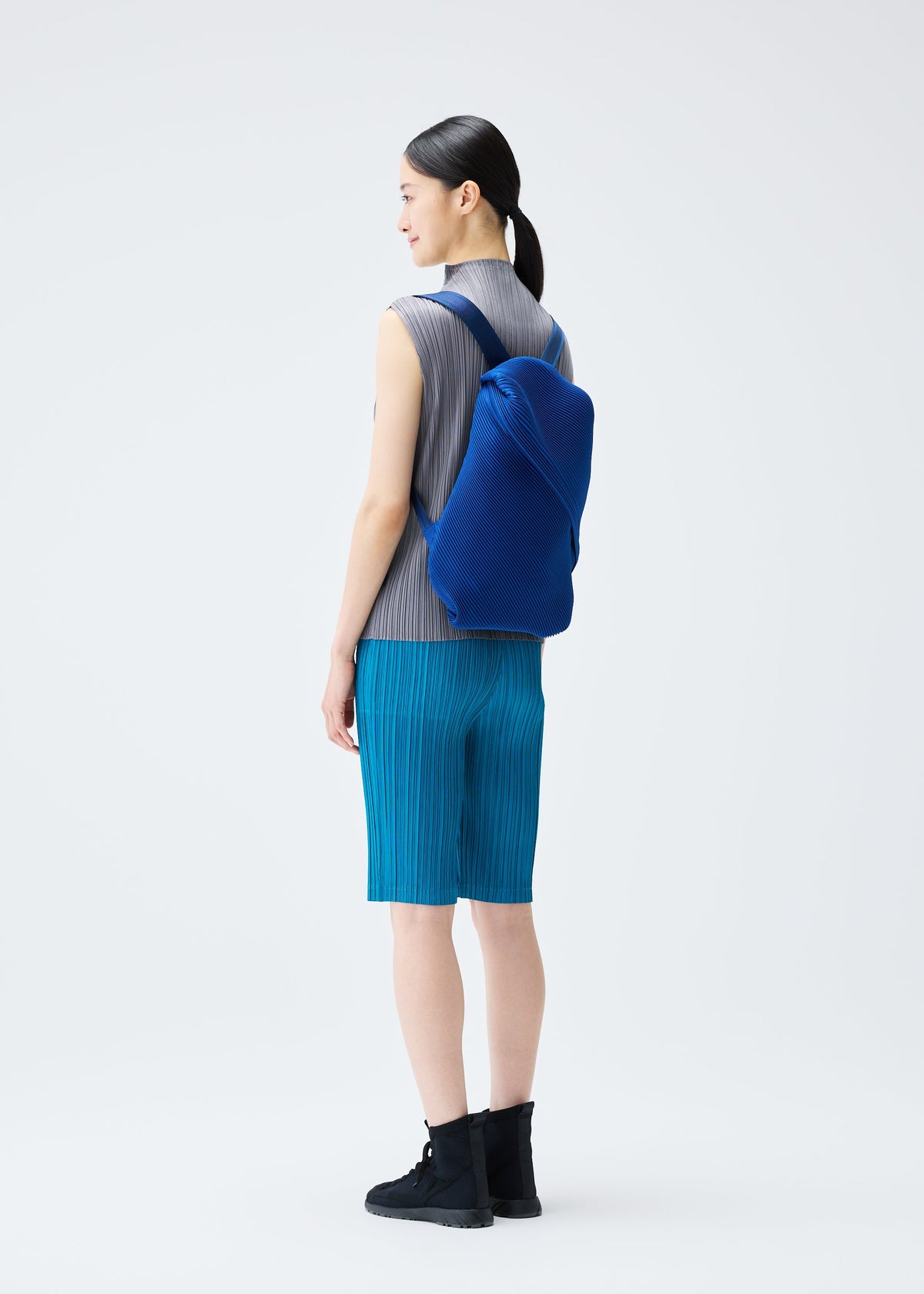 A model wears the PLEATS PLEASE ISSEY MIYAKE BIAS PLEATS BACKPACK bag.