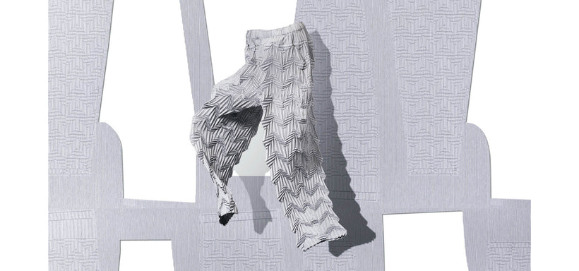 Centre: TYPE-O 019 Trousers White-Hued suspended mid-air. Background: A white sheet of trouser patten against a grey background. 