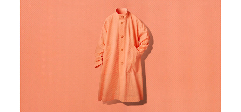 Centre: TYPE-T 001-1 Coat in Orange suspended mid-air against an orange fabric.