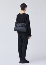 A model wears the BAO BAO ISSEY MIYAKE FROGGY shoulder bag.