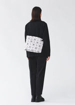 A model wears the BAO BAO ISSEY MIYAKE BLOCKY blocky-adjustable-shoulder-bag-matte-black.