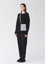 A model wears the BAO BAO ISSEY MIYAKE PRISM MATTE prism-matte-shoulder-bag-matte-black-1.