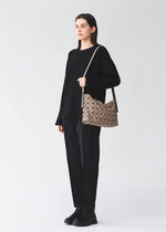 A model wears the BAO BAO ISSEY MIYAKE MUSETTE musette-shoulder-bag-11-inch-tablet-light-brown.