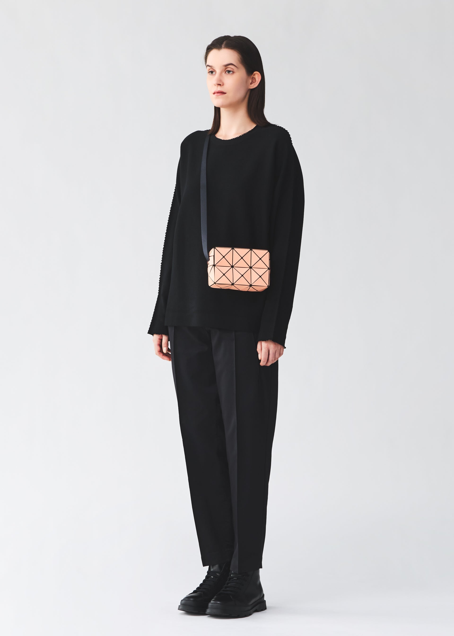 A model wears the BAO BAO ISSEY MIYAKE CUBOID cuboid-shoulder-bag-coral-orange.