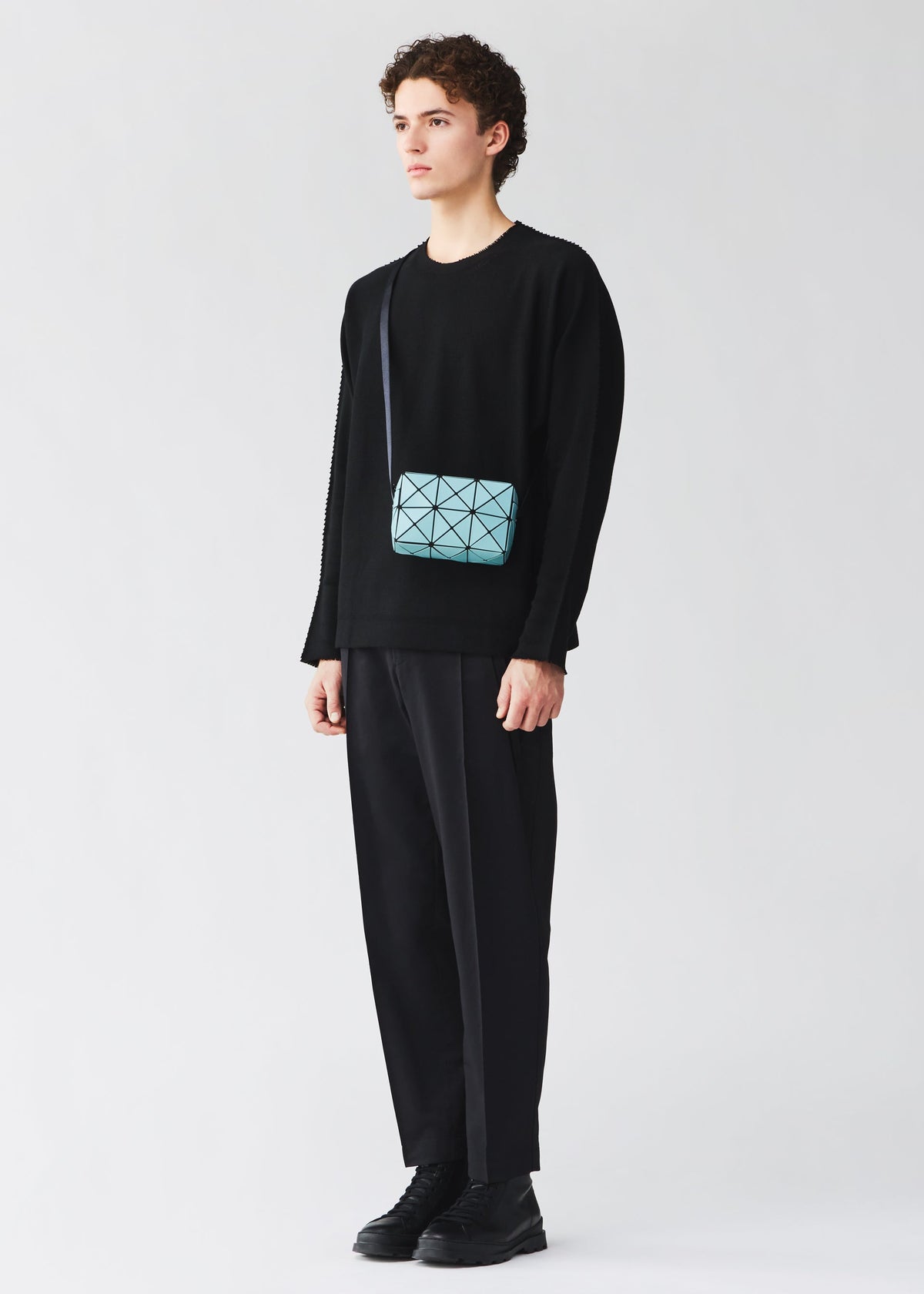 A model wears the BAO BAO ISSEY MIYAKE CUBOID cuboid-shoulder-bag-aqua-green.