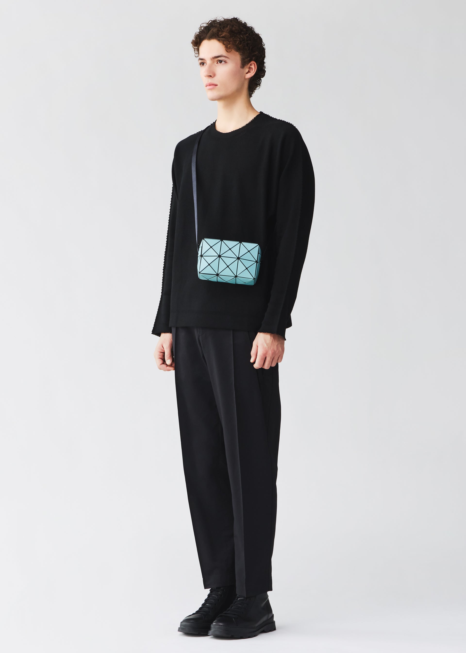 A model wears the BAO BAO ISSEY MIYAKE CUBOID cuboid-shoulder-bag-aqua-green.
