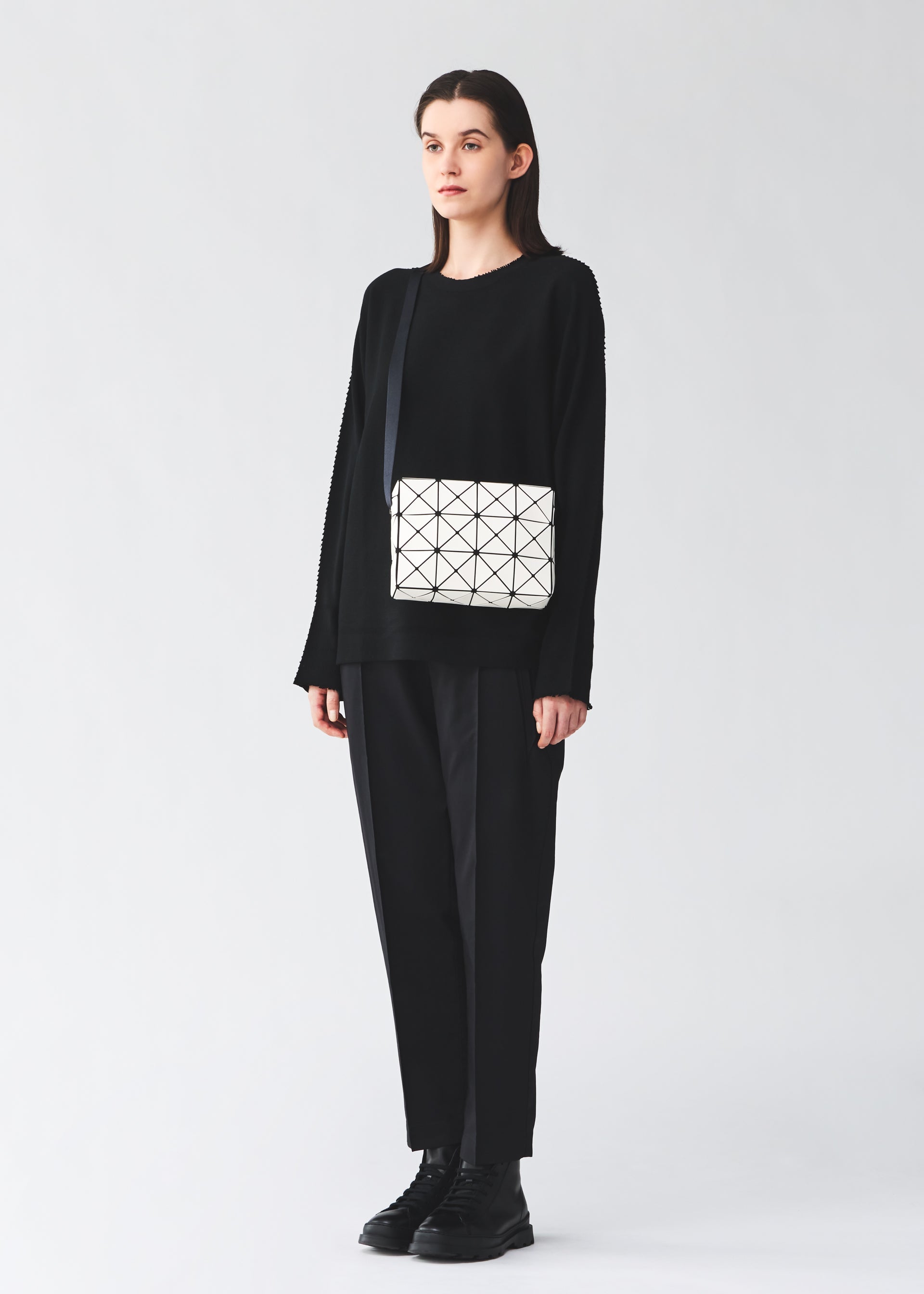 A model wears the BAO BAO ISSEY MIYAKE CUBOID cuboid-shoulder-bag-adjustable-strap-aqua-green.