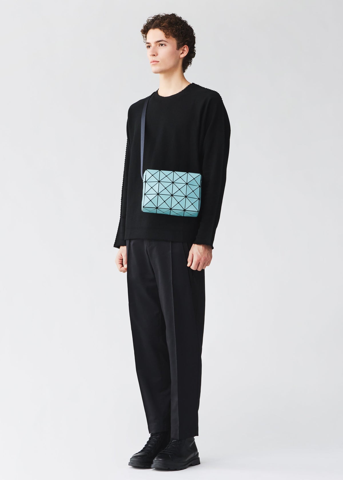 A model wears the BAO BAO ISSEY MIYAKE CUBOID cuboid-shoulder-bag-adjustable-strap-matte-black.