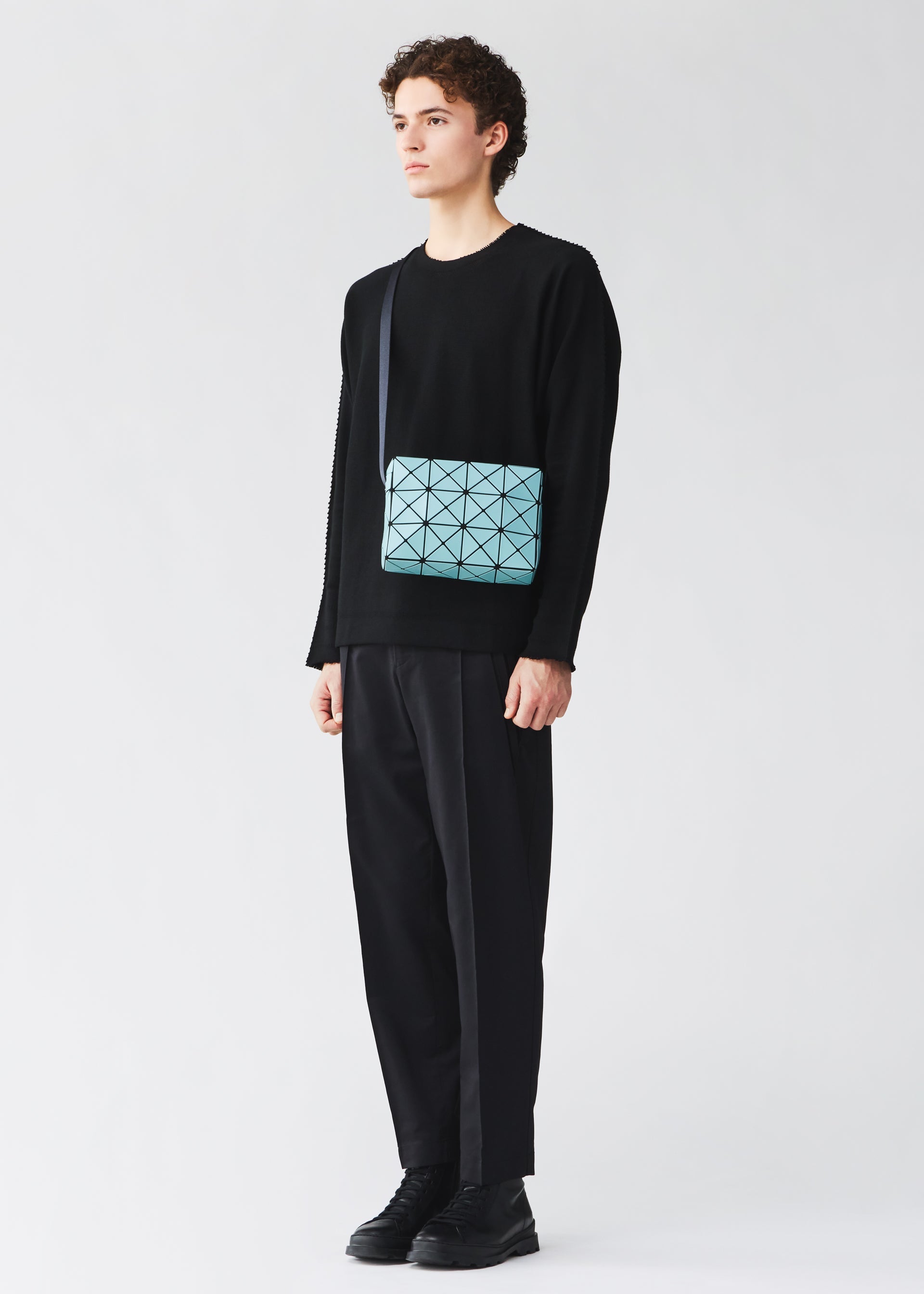 A model wears the BAO BAO ISSEY MIYAKE CUBOID cuboid-shoulder-bag-adjustable-strap-matte-black.