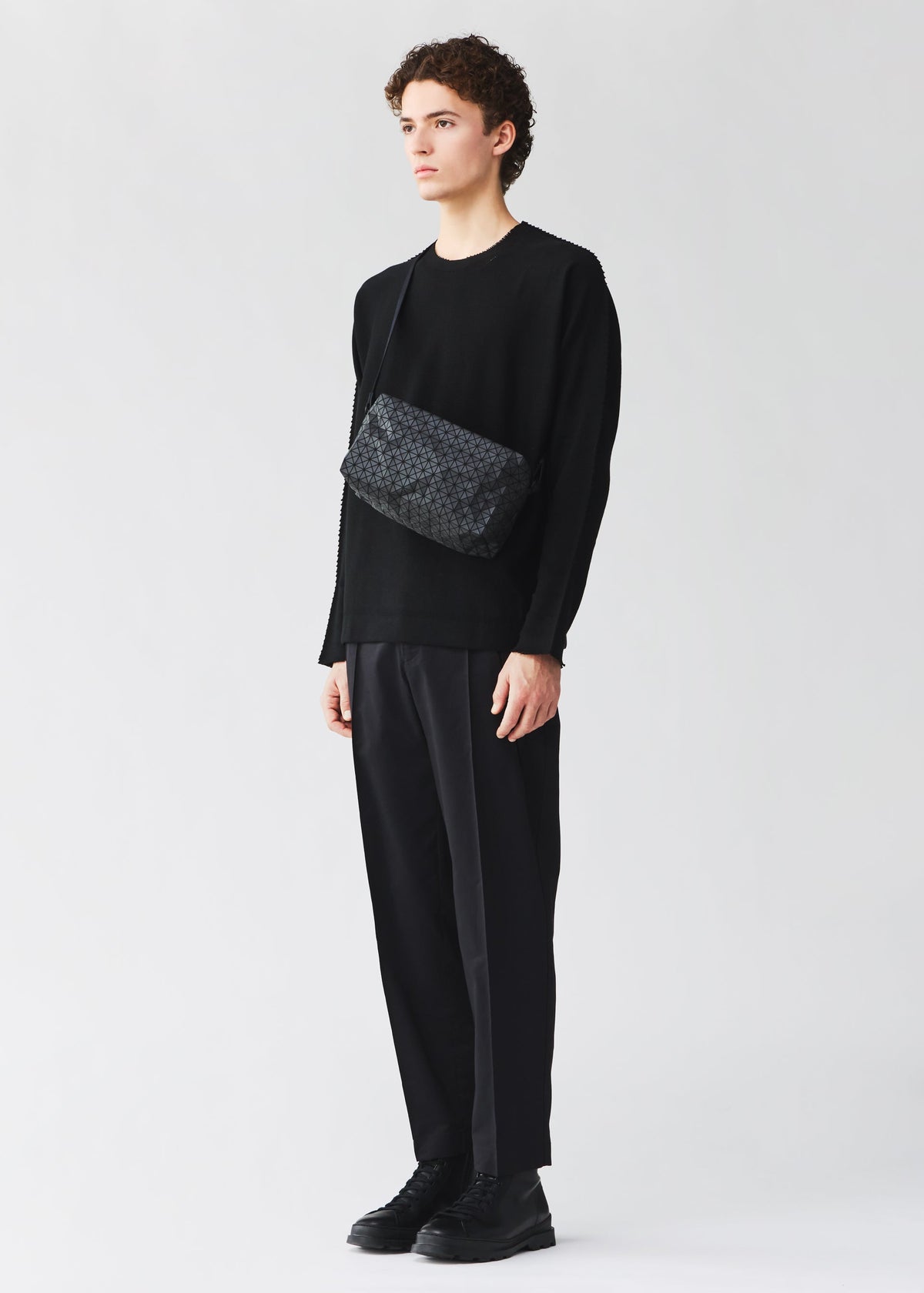 A model wears the BAO BAO ISSEY MIYAKE SADDLE BAG saddle-bag-shoulder-bag-matte-black-2.