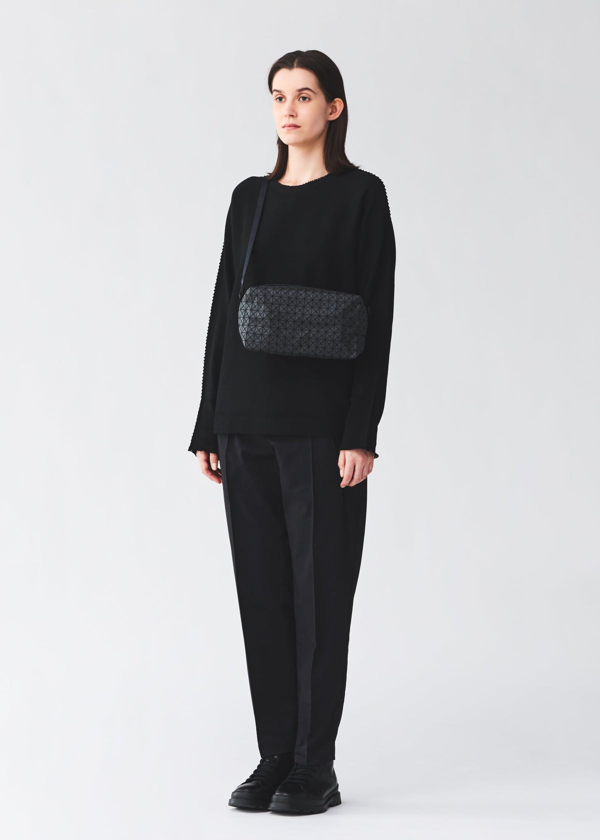 A model wears the BAO BAO ISSEY MIYAKE SADDLE BAG saddle-bag-shoulder-bag-matte-black-2.