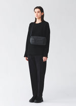 A model wears the BAO BAO ISSEY MIYAKE SADDLE BAG saddle-bag-shoulder-bag-matte-black-2.