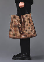 A model wears the BAO BAO ISSEY MIYAKE CART REFLECTOR cart-reflector-tote-copper-brown.