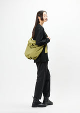 A model wears the GOOD GOODS ISSEY MIYAKE FUWA FUWA bag.