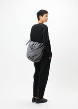 A model wears the GOOD GOODS ISSEY MIYAKE FUWA FUWA bag.