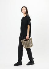 A model wears the GOOD GOODS ISSEY MIYAKE MOKKO bag.