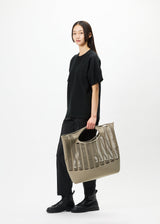 A model wears the GOOD GOODS ISSEY MIYAKE MOKKO bag.