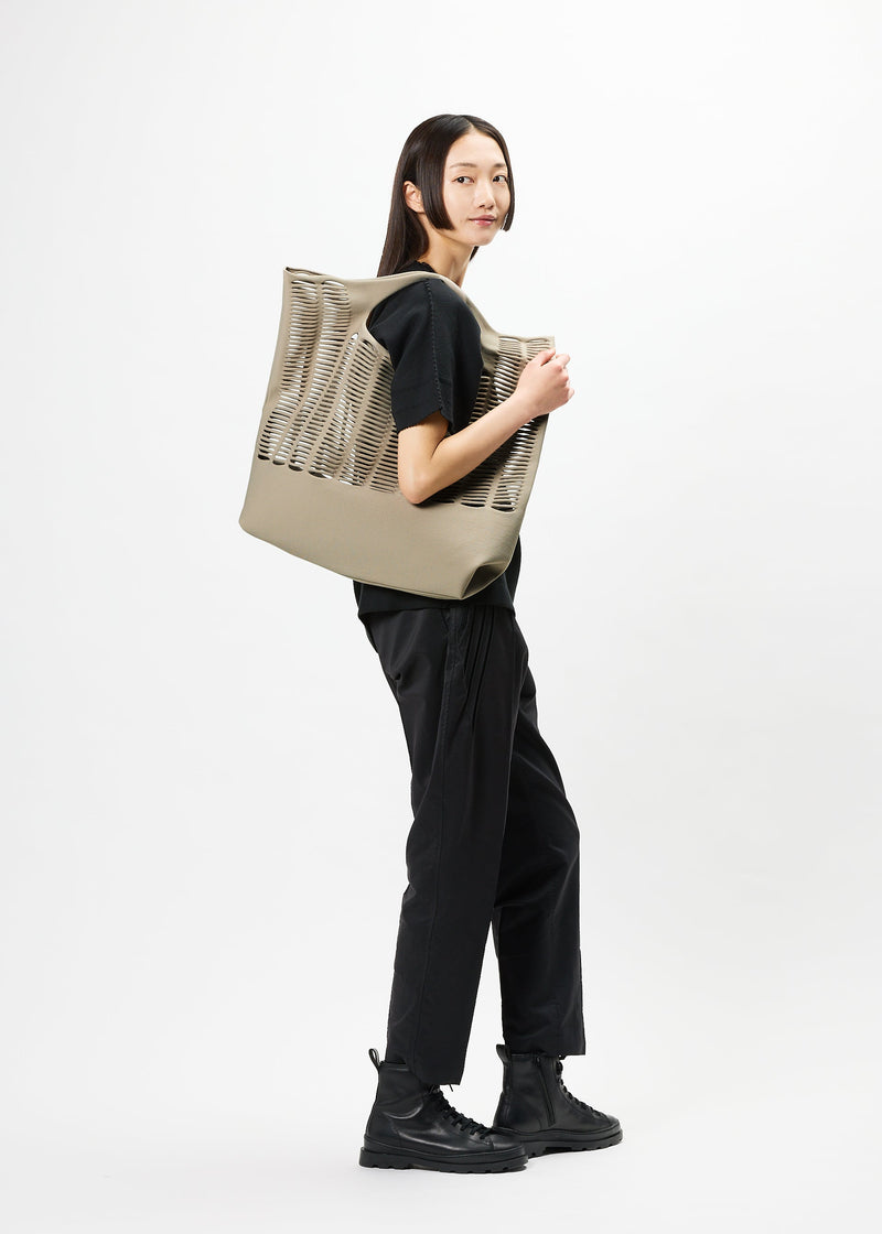 A model wears the GOOD GOODS ISSEY MIYAKE MOKKO bag.