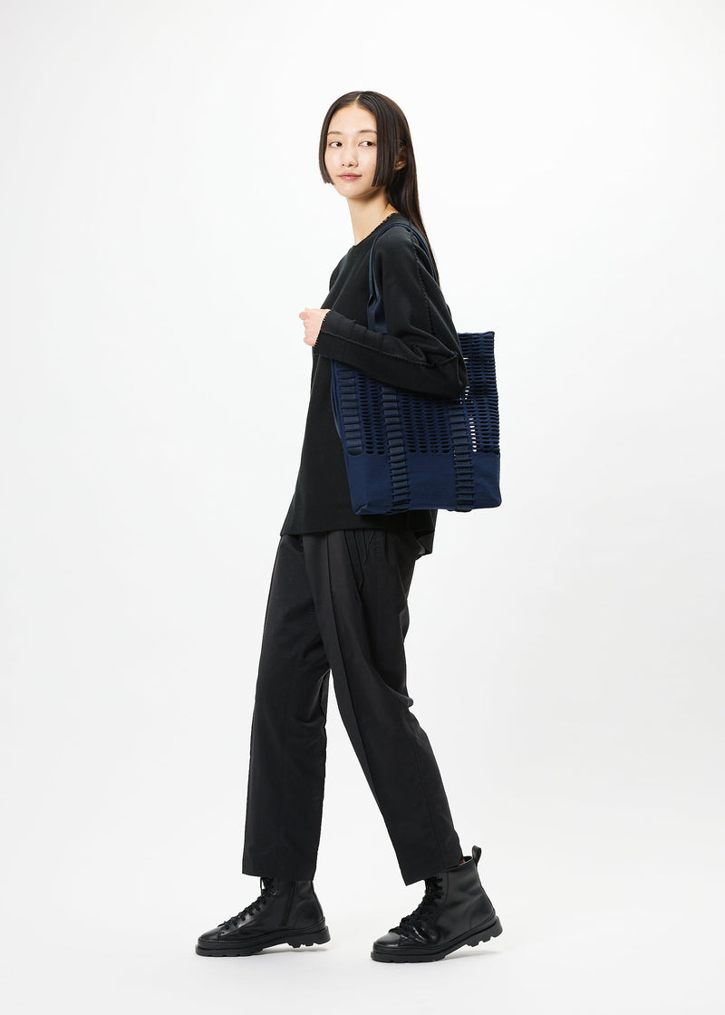 A model wears the GOOD GOODS ISSEY MIYAKE MOKKO MONO bag.