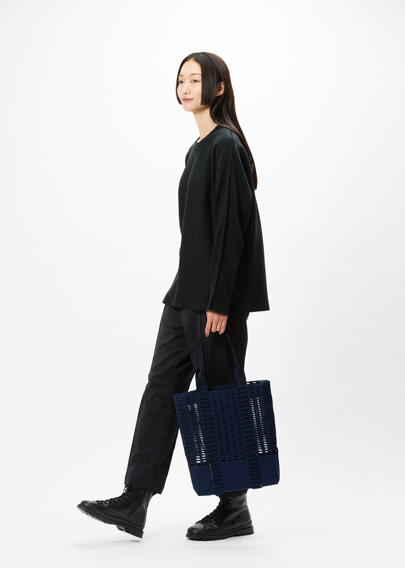 A model wears the GOOD GOODS ISSEY MIYAKE MOKKO MONO bag.