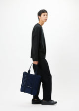 A model wears the GOOD GOODS ISSEY MIYAKE MOKKO MONO bag.