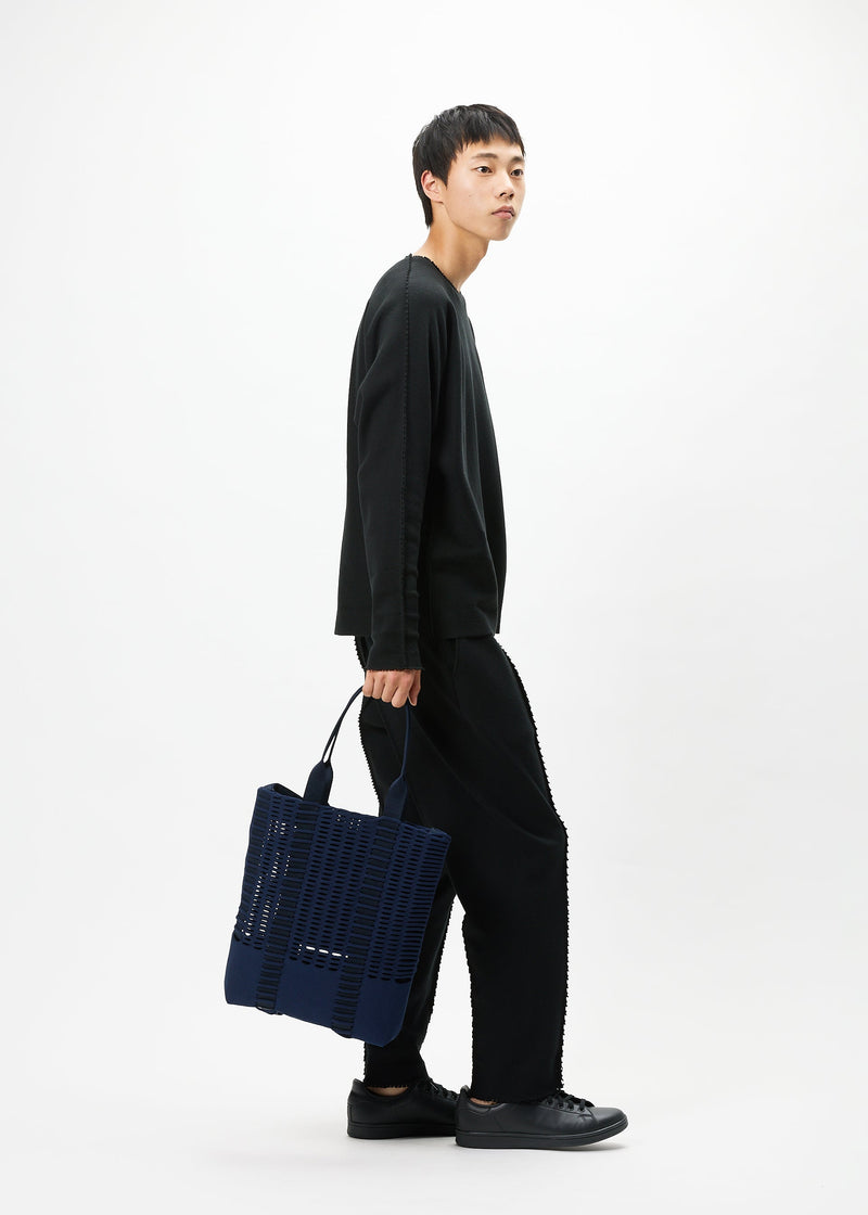 A model wears the GOOD GOODS ISSEY MIYAKE MOKKO MONO bag.