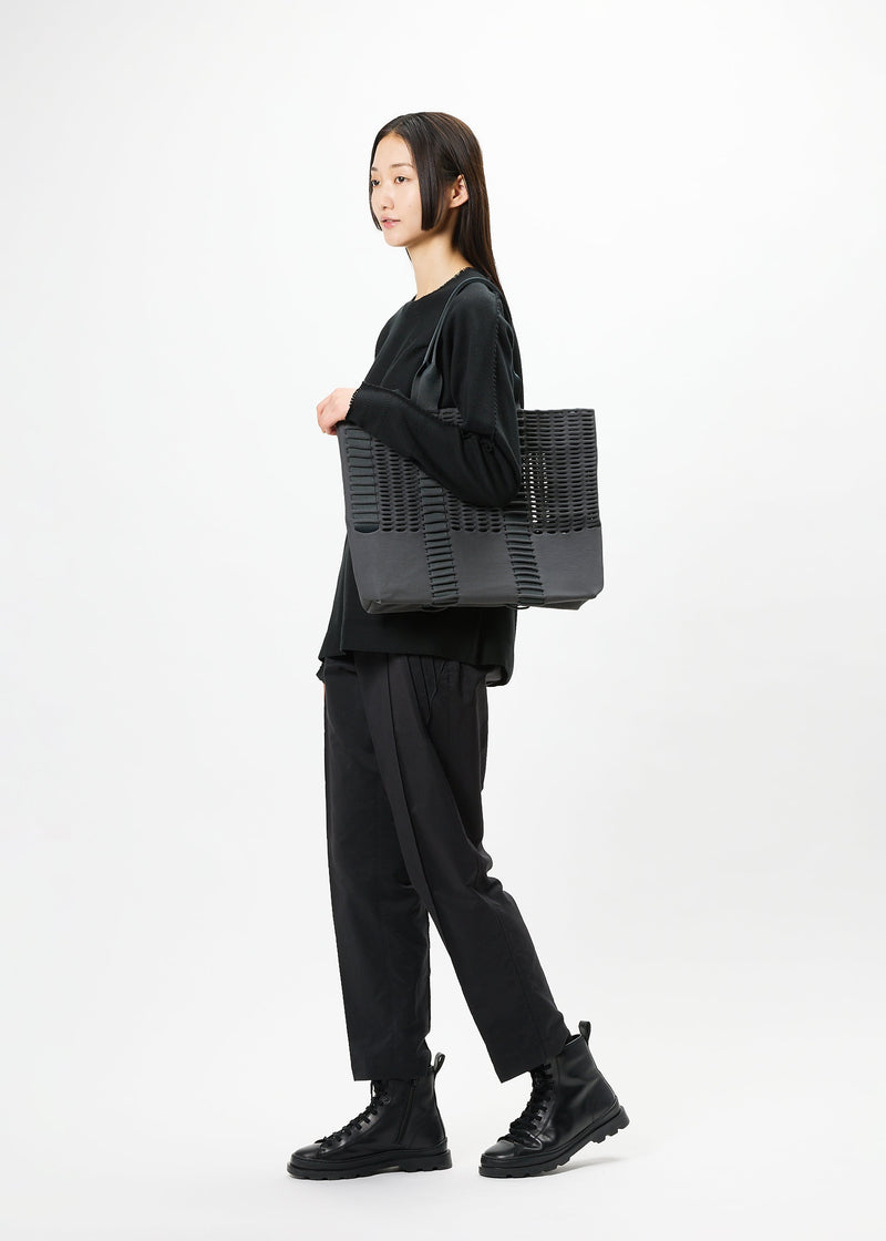 A model wears the GOOD GOODS ISSEY MIYAKE MOKKO MONO bag.