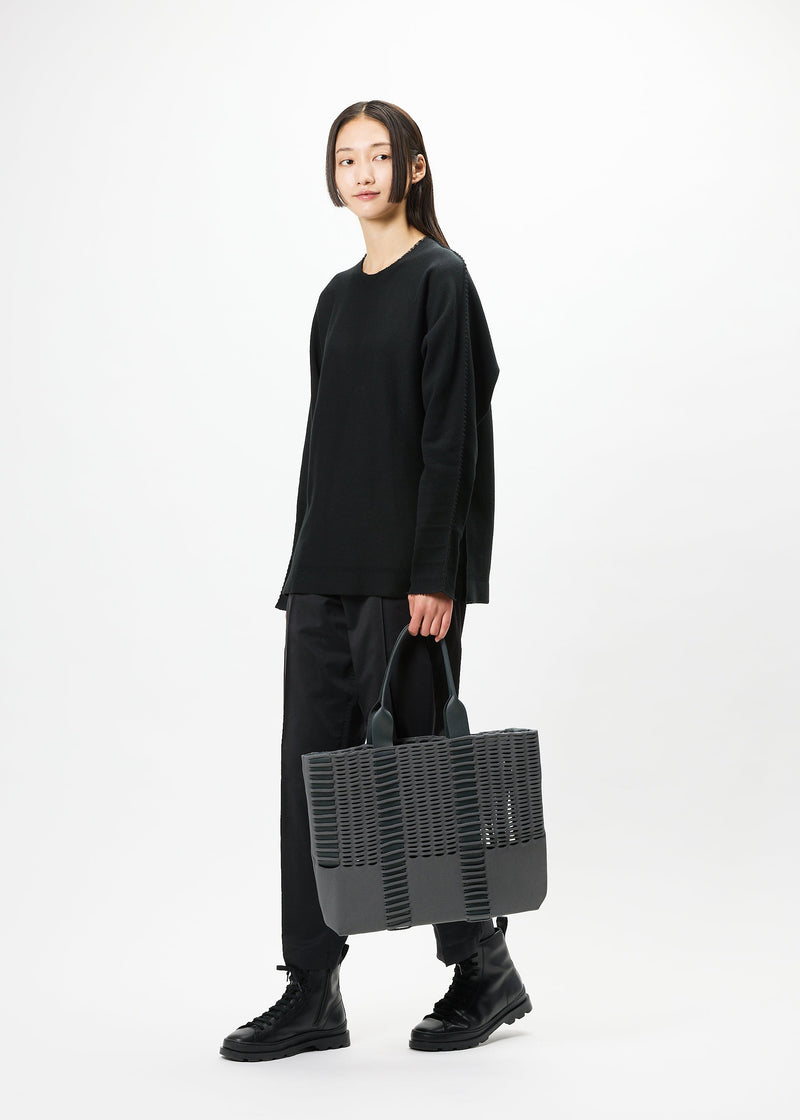 A model wears the GOOD GOODS ISSEY MIYAKE MOKKO MONO bag.