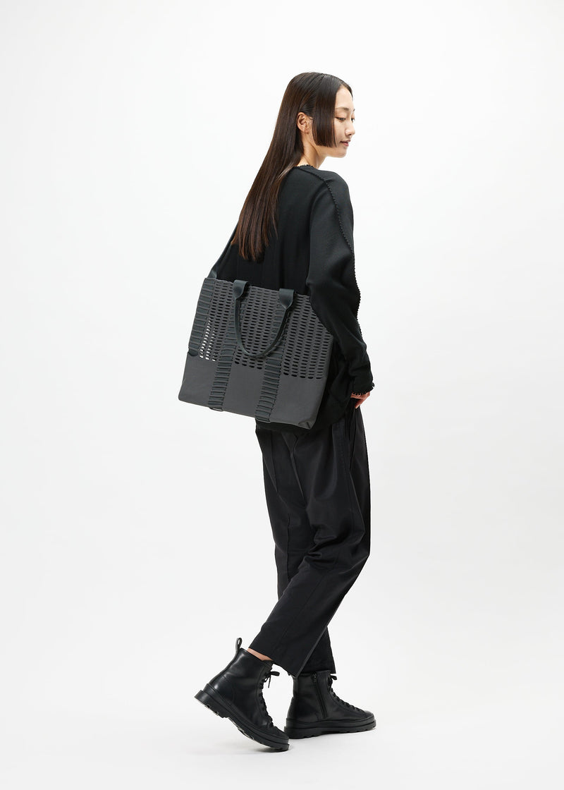 A model wears the GOOD GOODS ISSEY MIYAKE MOKKO MONO bag.