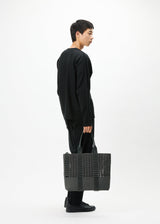 A model wears the GOOD GOODS ISSEY MIYAKE MOKKO MONO bag.