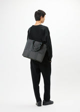 A model wears the GOOD GOODS ISSEY MIYAKE MOKKO MONO bag.