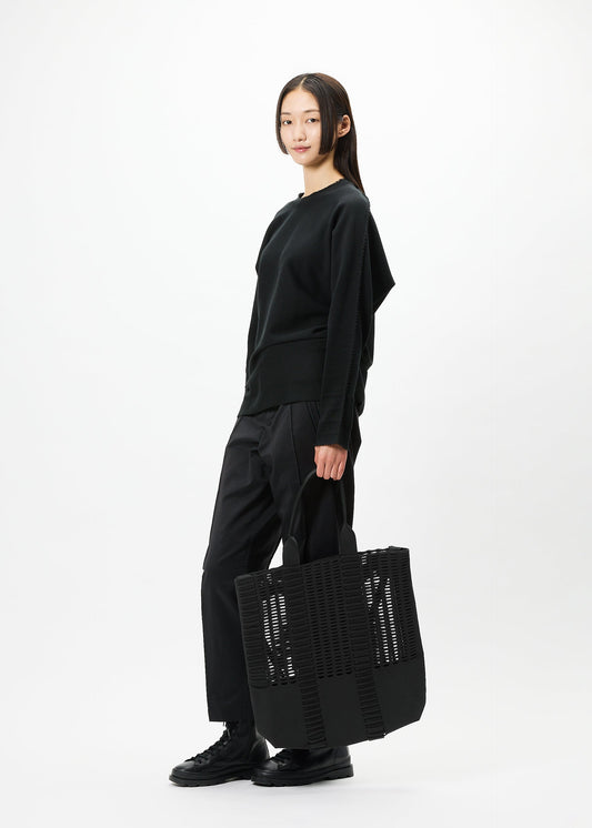 A model wears the GOOD GOODS ISSEY MIYAKE MOKKO MONO bag.