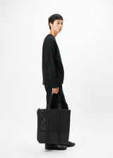 A model wears the GOOD GOODS ISSEY MIYAKE MOKKO MONO bag.