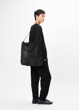 A model wears the GOOD GOODS ISSEY MIYAKE MOKKO MONO bag.