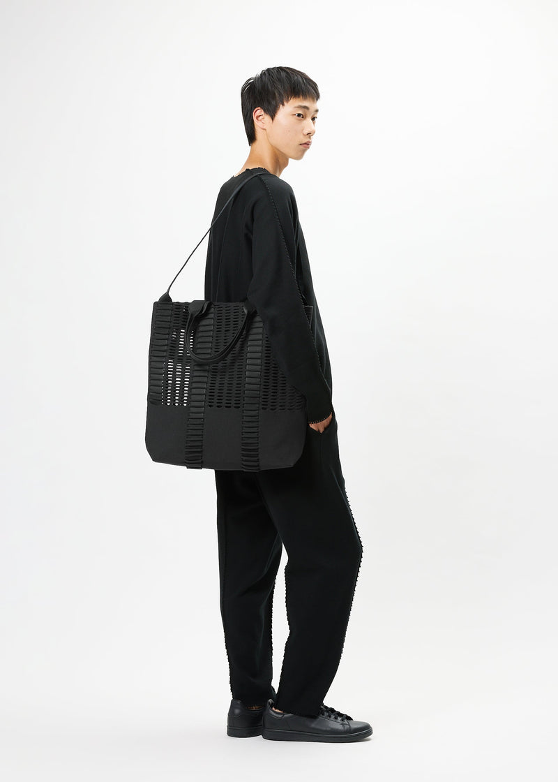 A model wears the GOOD GOODS ISSEY MIYAKE MOKKO MONO bag.