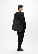 A model wears the GOOD GOODS ISSEY MIYAKE MOKKO MONO bag.