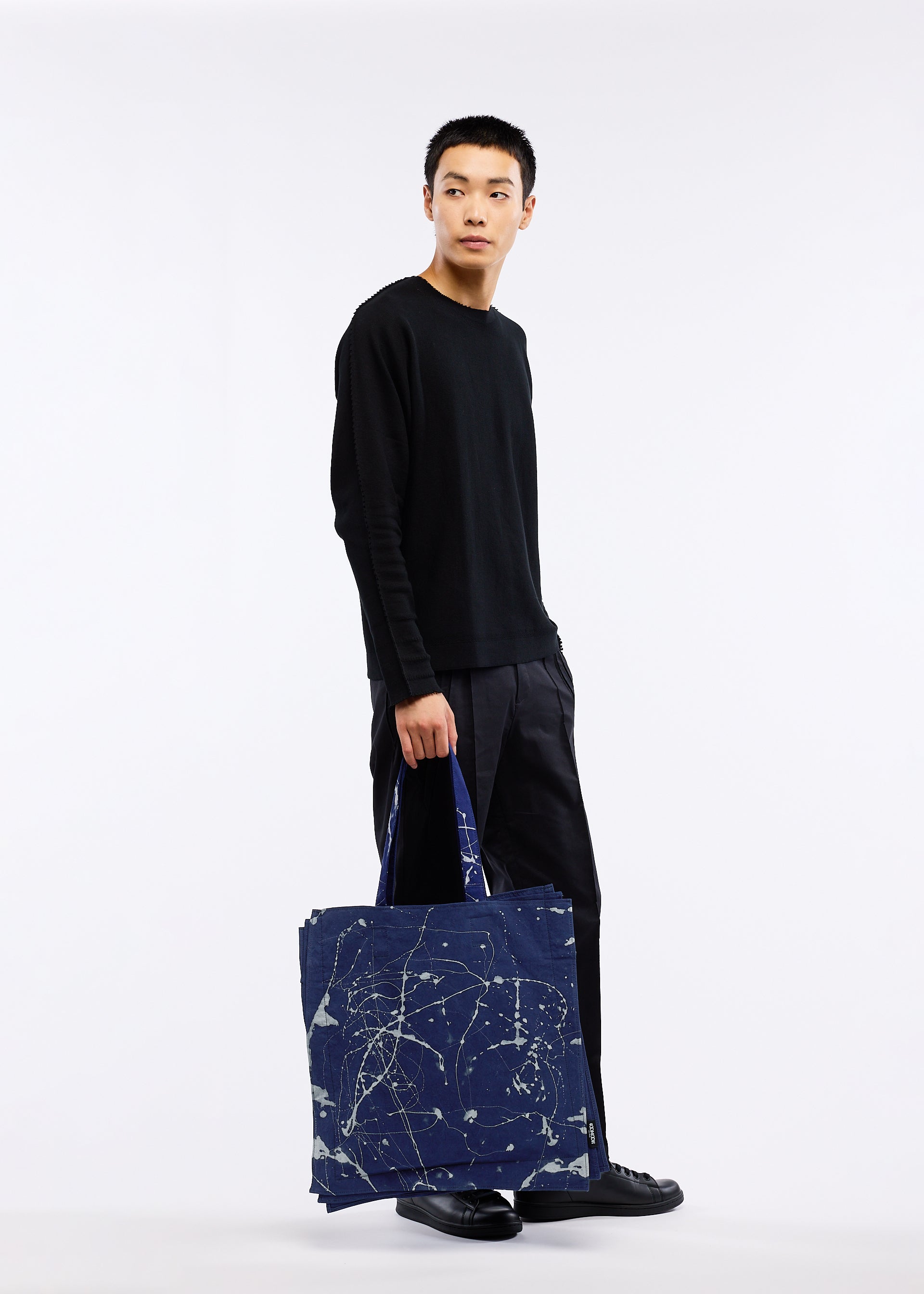 A model wears the GOOD GOODS ISSEY MIYAKE IROGAMI BASSEN bag.