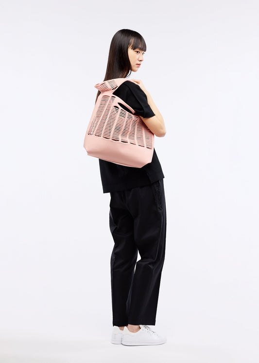 A model wears the GOOD GOODS ISSEY MIYAKE MOKKO TOWN SHOULDER bag.