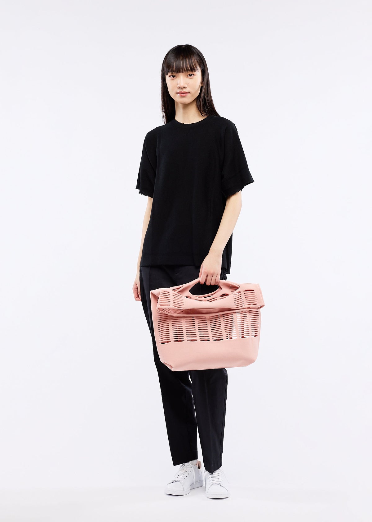 A model wears the GOOD GOODS ISSEY MIYAKE MOKKO TOWN SHOULDER bag.