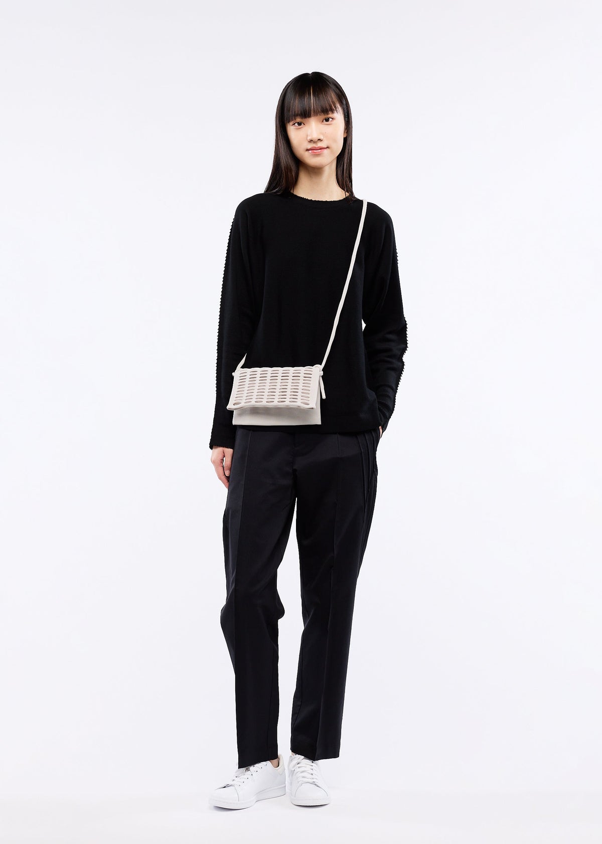 A model wears the GOOD GOODS ISSEY MIYAKE MOKKO FLAP POUCH bag.