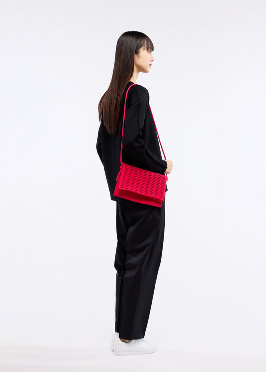 A model wears the GOOD GOODS ISSEY MIYAKE MOKKO FLAP POUCH bag.