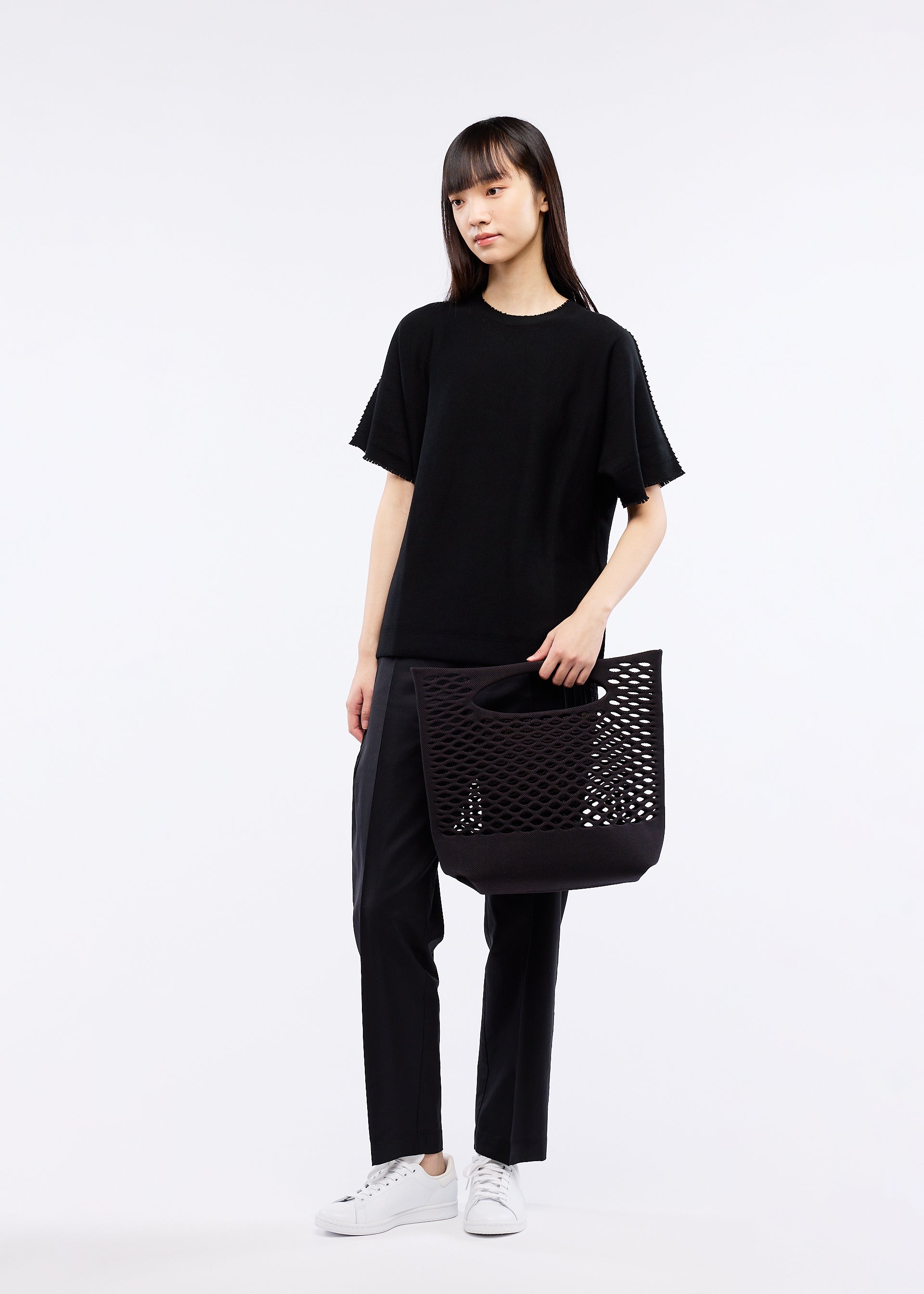 A model wears the GOOD GOODS ISSEY MIYAKE MOKKO BASKET bag.