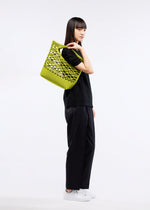 A model wears the GOOD GOODS ISSEY MIYAKE MOKKO BASKET bag.