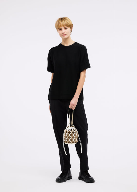 A model wears the GOOD GOODS ISSEY MIYAKE AMIME bag.