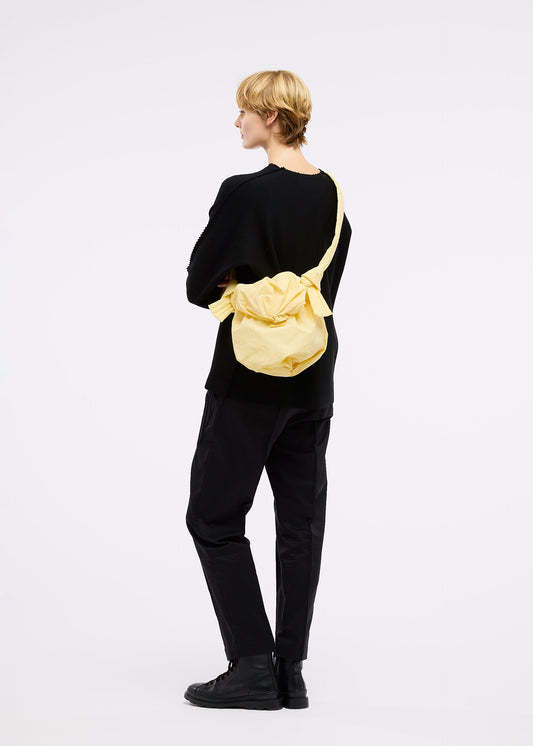 A model wears the GOOD GOODS ISSEY MIYAKE FUWA FUWA bag.