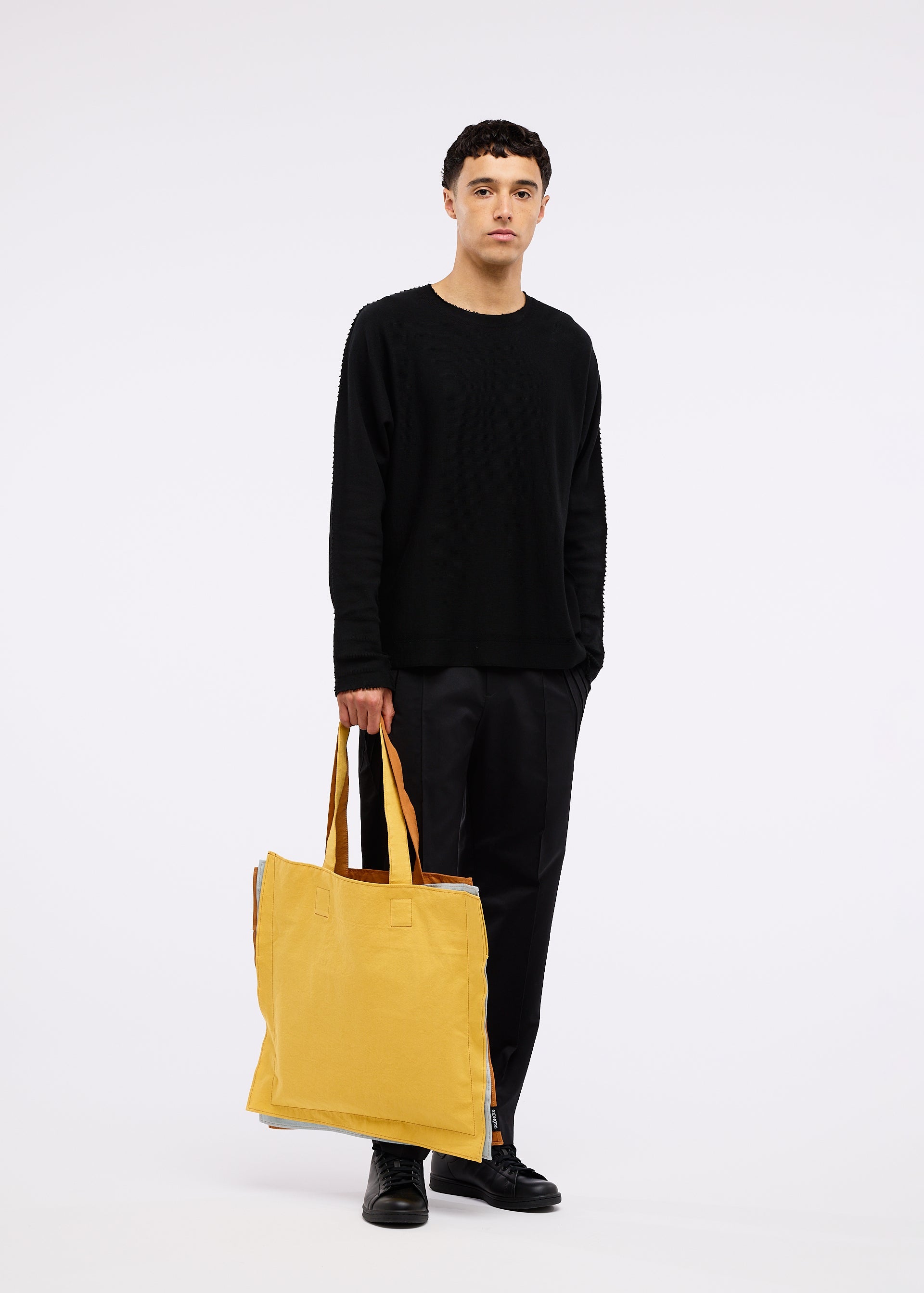 A model wears the GOOD GOODS ISSEY MIYAKE IROGAMI bag.